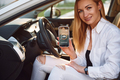 WIth smartphone. Young woman in white clothes is with her electric car at daytime - PhotoDune Item for Sale