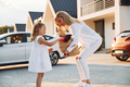 holding bags with products. Young woman with her little daughter is with their electric car outdoors - PhotoDune Item for Sale
