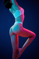 View from the side. Young woman in underwear is in the studio with neon lights - PhotoDune Item for Sale