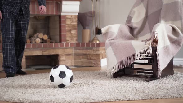 Unrecognizable Caucasian Old Man in Pajamas Hitting Ball and Walking Away. Elderly Soccer Player