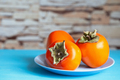 Persimmon on blue plate against background of stone wall - PhotoDune Item for Sale