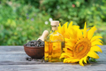 Sunflower seeds and flowers with bottle of oil on wooden table - PhotoDune Item for Sale