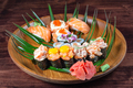 Sushi and rolls with raw quail eggs on wooden plate with green leaves - PhotoDune Item for Sale