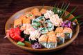 Sushi and rolls with sauce and spices on wooden plate with green leaves - PhotoDune Item for Sale