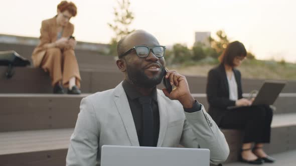 Black Businessman Speaking on Phone while Working Outdoors