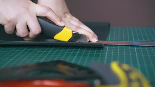 Person Cuts Black Leather Fabric with Special Box Cutter