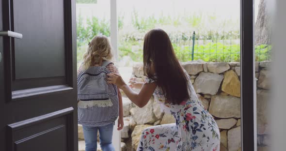 Mother embracing her daughter before leaving school at door in home 4k