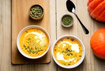 Yellow Pumpkin Soup with cream, pumpkin seed, and parsley on wooden background. Copy space. Top view