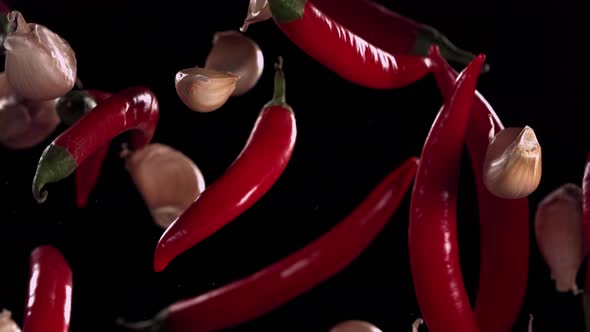 Super Slow Motion Shot of Flying Red Chilli Peppers and Garlic