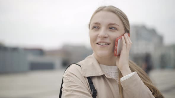 Camera Moves Around Beautiful Face of Young Charming Caucasian Woman Talking on Smartphone. Close-up