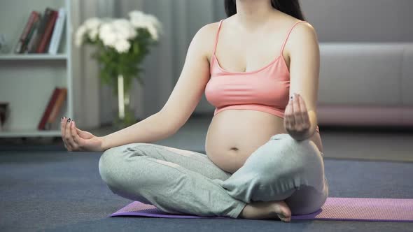 Pregnant Woman Practicing Yoga at Home, Calming Herself and Her Future Baby