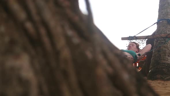 HIKKADUWA, SRI LANKA - FEBRUARY 2014: The view of a woman sleeping in a hammock on a beach in Hikkad