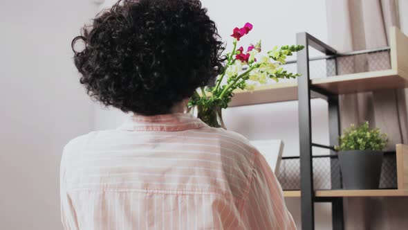 Woman Putting Flowers on Shelving at Home