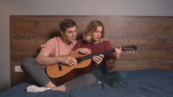 the Pair Play Acoustic and Electric Guitar Together. Beautiful Young Man Teaches His Girlfriend To