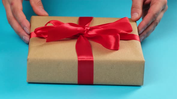 female hands hold a wrapped box in brown kraft paper