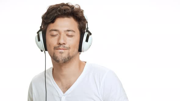 Young Handsome Man Smiling Listening Music in Headphones Dancing Over White Background