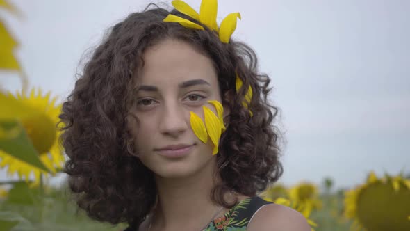 Portrait of Beautiful Curly Playful Girl Looking at the Camera Standing on the Sunflower Field