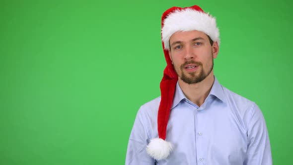 A Young Handsome Man in a Christmas Hat Talks Seriously To the Camera - Green Screen Studio