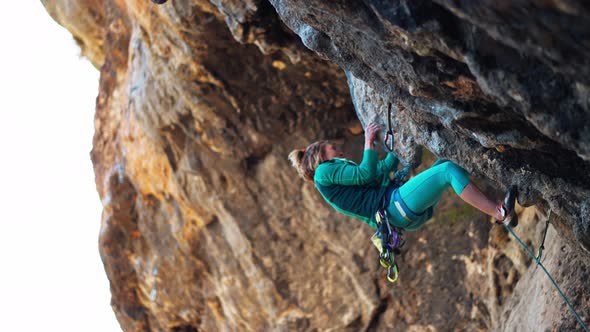 Strong Woman Rock Climber Climbs Hard Tough Rock Route on Very Overhanging Black Cliff in Turkey