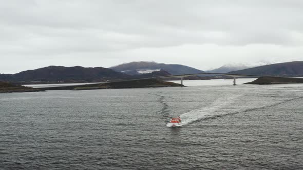 Boat Cruising At Norwegian Sea With Storseisundet Bridge In Background In Norway.