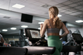 Rear view of caucasian woman running on treadmill at fitness center - PhotoDune Item for Sale