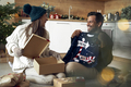 Multi ethnicity couple opening Christmas presents at home - PhotoDune Item for Sale