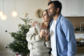 Multi ethnicity couple standing at home at Christmas time and looking away - PhotoDune Item for Sale