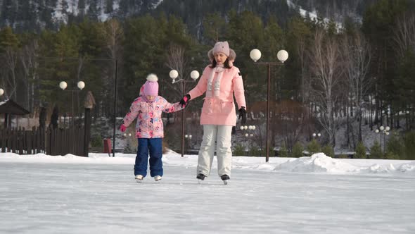 Woman with Daughter Skating on Scenic Ice Rink