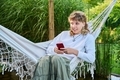Teenage girl sitting in hammock using smartphone for leisure study communication - PhotoDune Item for Sale