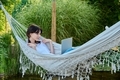 Teenage girl relaxing in hammock using laptop for leisure study - PhotoDune Item for Sale