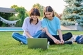 Two teenage friends of students sitting on grass with laptop, in backyard - PhotoDune Item for Sale
