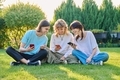 Teenage friends sitting on the grass with smartphones - PhotoDune Item for Sale