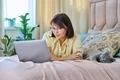 Middle aged woman relaxing at home on bed with laptop and pet cat - PhotoDune Item for Sale