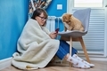 Woman at home using smartphone, warming with cat near heating radiator - PhotoDune Item for Sale