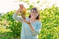 Smiling woman holding bunch of pink grapes, vineyard background - PhotoDune Item for Sale