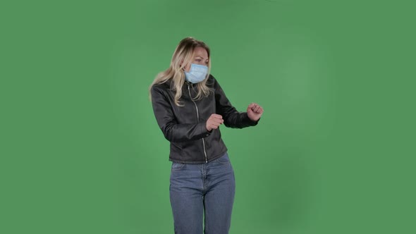 Portrait of Beautiful Young Woman in Medical Mask Is Looking Straight and Is Dancing Funny. Blonde