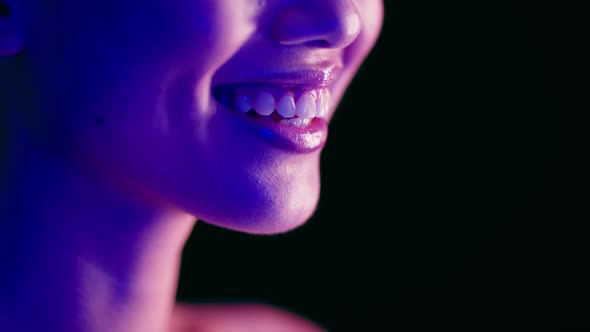 Closeup Shot Of Young Woman's Smile Illuminated With Colorful Neon Light