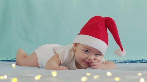 Funny Little Baby Smiling. Cute Infant Boy Wearing Santa Hat Lying on Sofa.