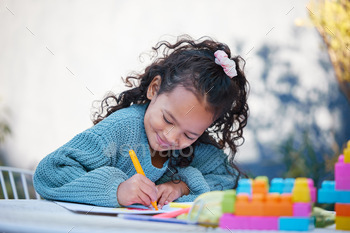 I love putting bright colours on a page. Shot of a little girl completing homework in her yard.