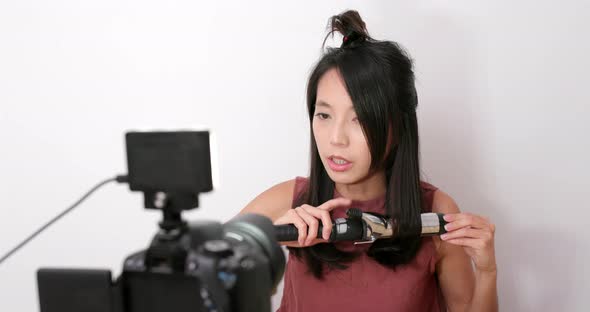 Woman making hair with using hair curler in front of the camera at home