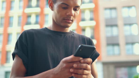 Young Man Holding Smartphone on the Street in Modern City