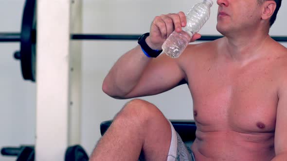 Sweaty Shirtless Man Drinking Water From a Bottle