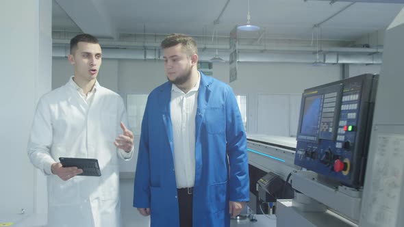 Colleagues Discussing Work of Conveyor Equipment at Factory