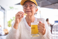 Portrait of attractive mature woman holding a glass of iced beer eating a potato snack - PhotoDune Item for Sale