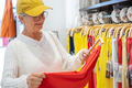 Senior woman with hat and eyeglasses in modern store choosing colorful new clothes. - PhotoDune Item for Sale