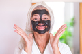 Carefree senior beautiful woman with a detox facial charcoal mask homemade smiling looking at camera - PhotoDune Item for Sale