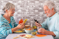 Beautiful caucasian senior couple sitting face to face at table using their mobile phones - PhotoDune Item for Sale