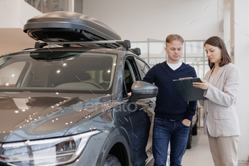person and car rental helps with the purchase. signing a trade-in contract and handing over keys, shaking hands. A successful man chooses a new car
