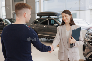 person and car rental helps with the purchase. signing a trade-in contract and handing over keys, shaking hands. A successful man chooses a new car