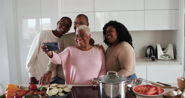 Happy latin family cooking inside kitchen at home and taking a selfie with mobile phone
